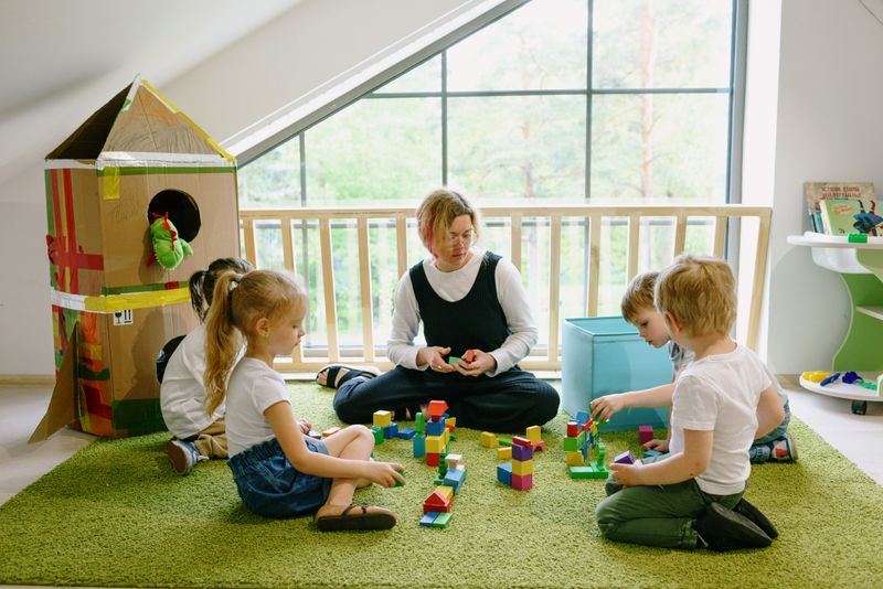 Children building with blocks alongside their educator