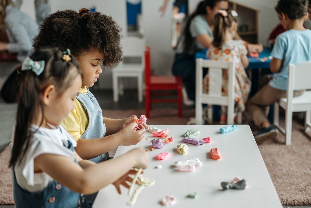Early learners shaping clay at a table, building fine motor skills