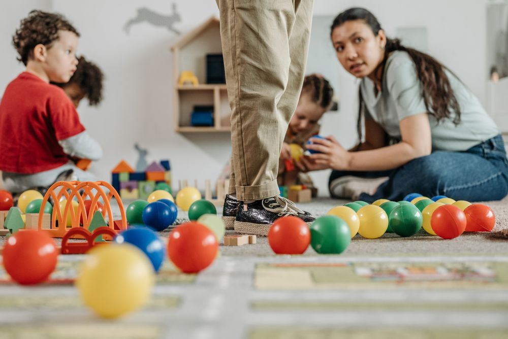 Toddlers playing on the floor with a caring educator